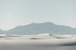 Dunas de areia brancas com uma cadeia montanhosa distante.