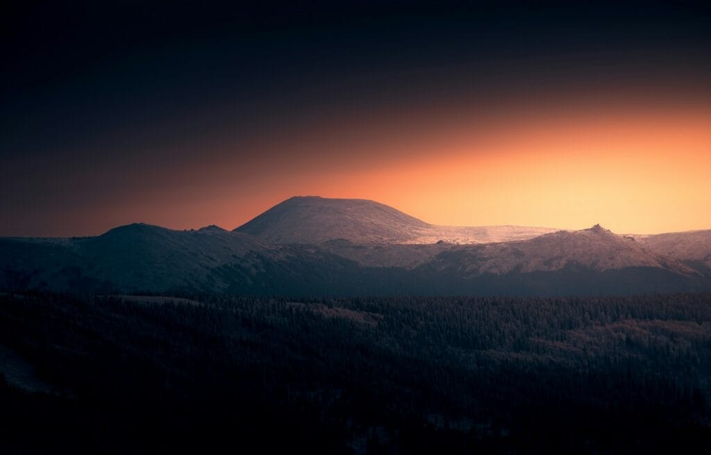 Silhueta de montanha contra um céu vibrante ao pôr do sol.