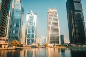 Arranha-céus modernos refletem-se na água de uma cidade.