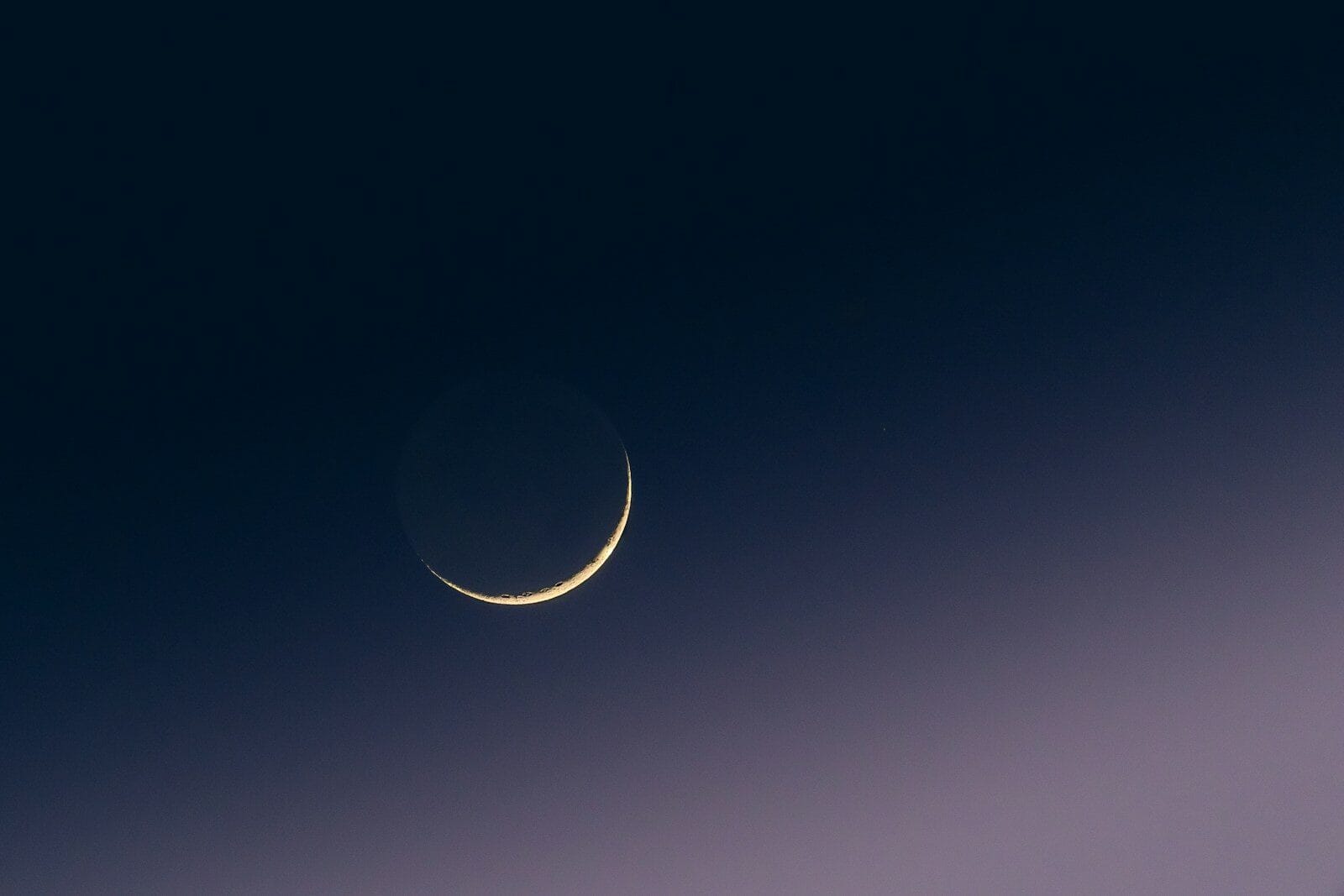 Lua crescente num céu escuro e degradado.