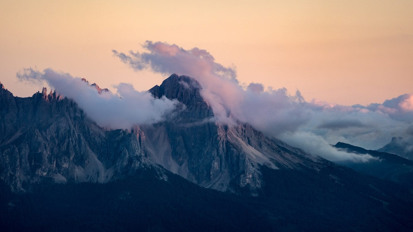 Picos enevoados ao nascer do sol com céu suave em tons pastel